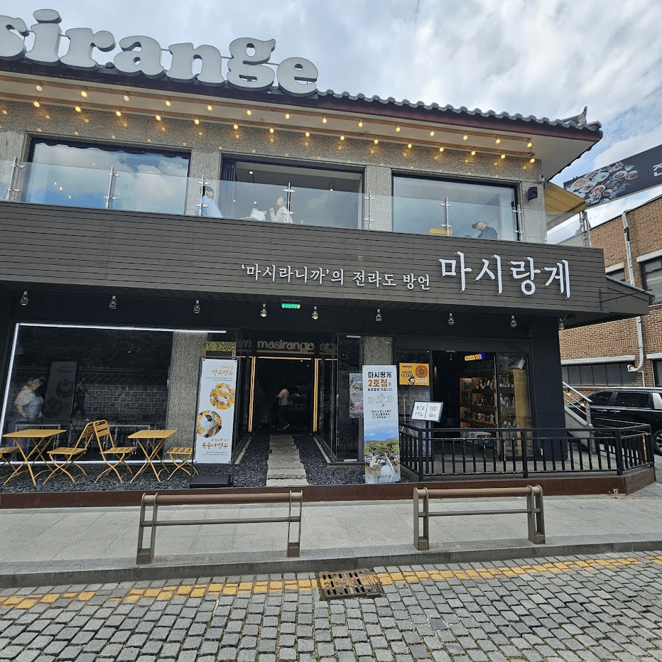 Traditional hanok cafe Masirange in Jeonju, showcasing a serene courtyard and tiled roof during rainfall.